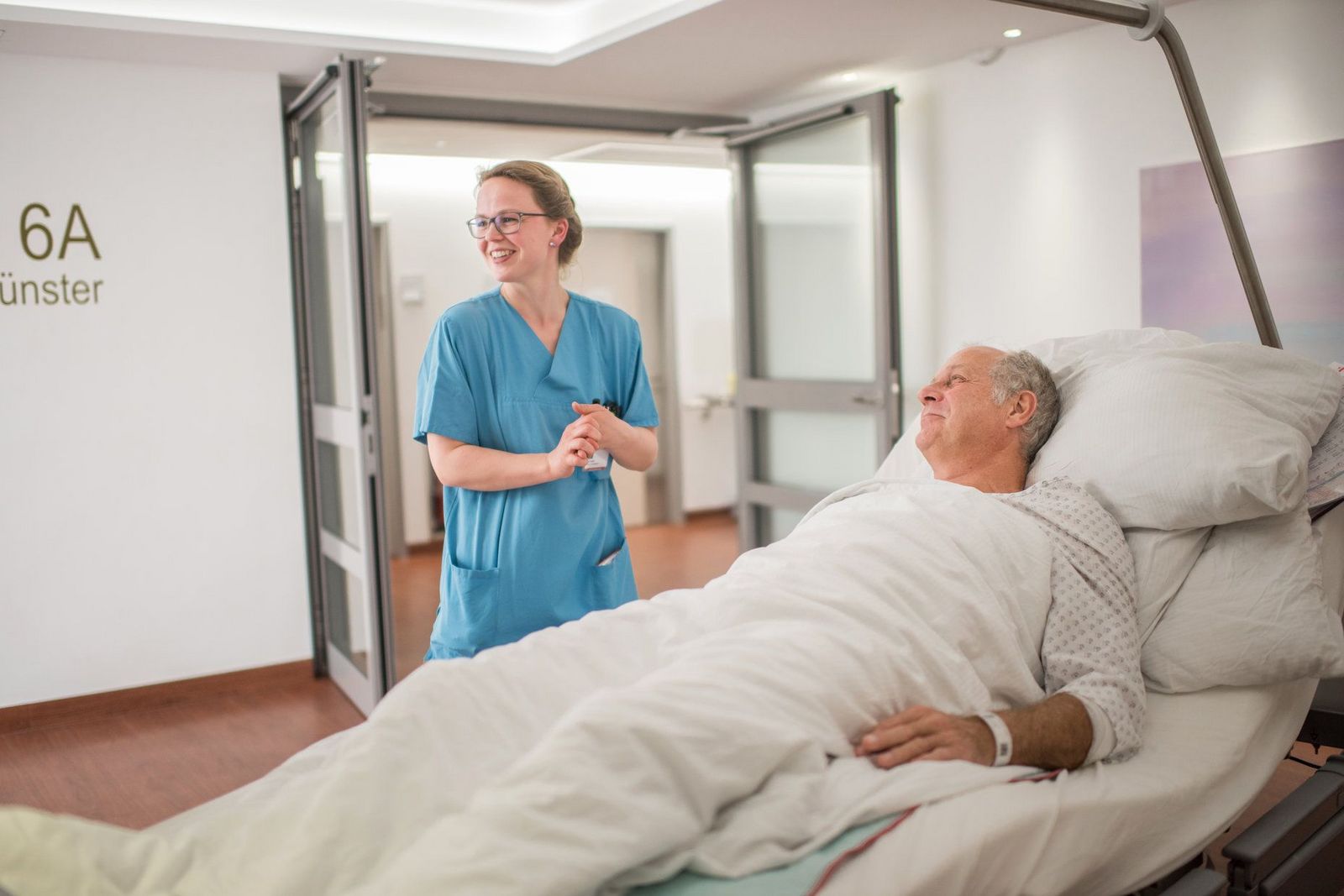 Eine Gesundheits- und Krankenpflegerin lacht mit einem Patienten