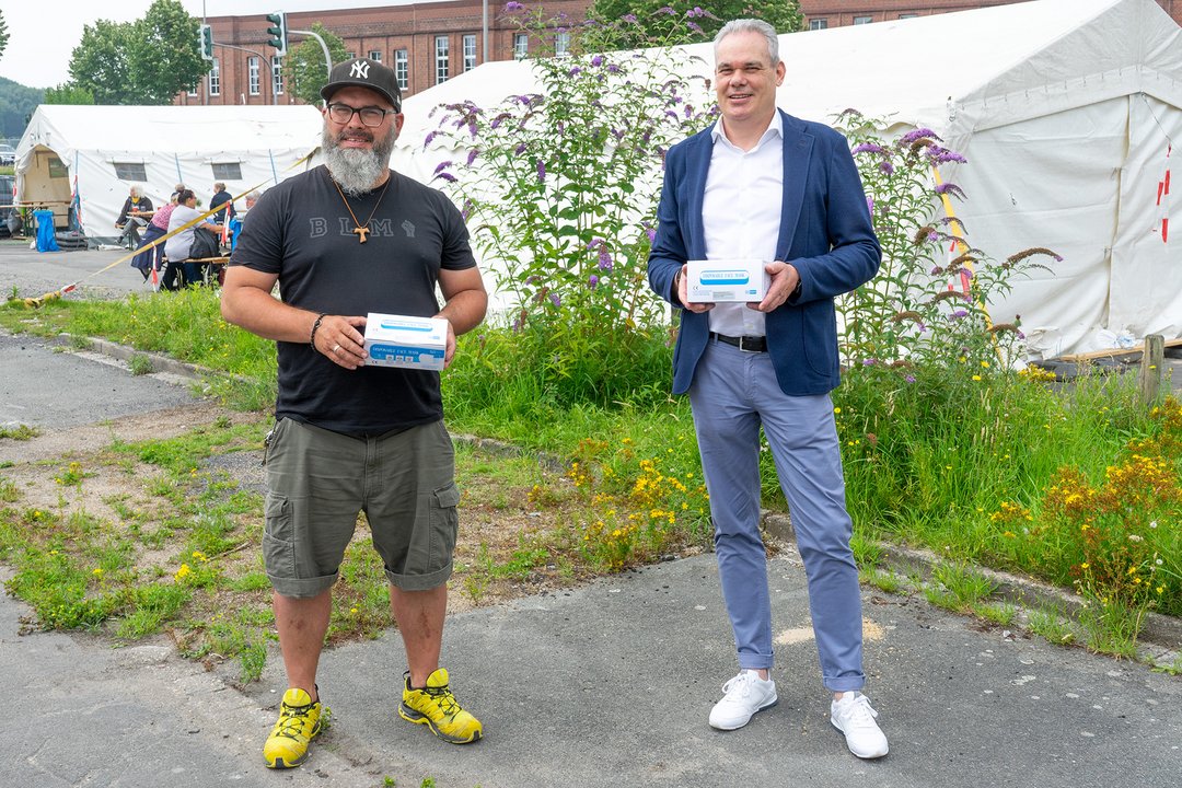 Zwei Männer halten Kästen mit Masken 