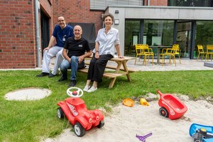 Drei Personen sitzen auf einer Gartenbank