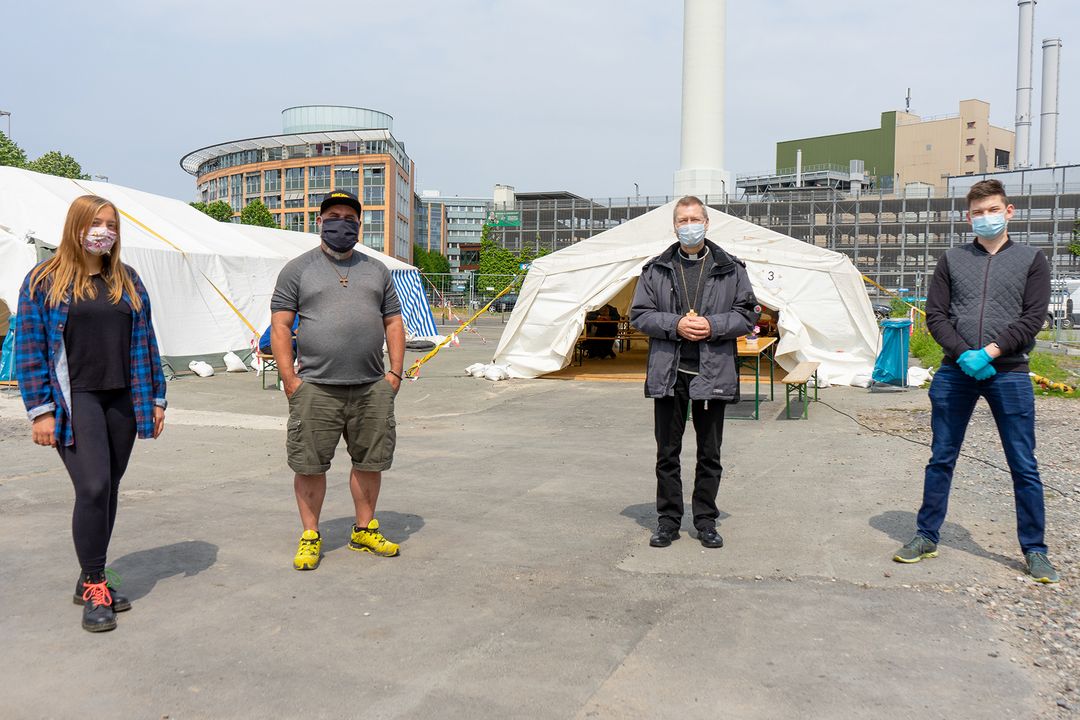 Vier Personen stehen vor einem großen Zelt
