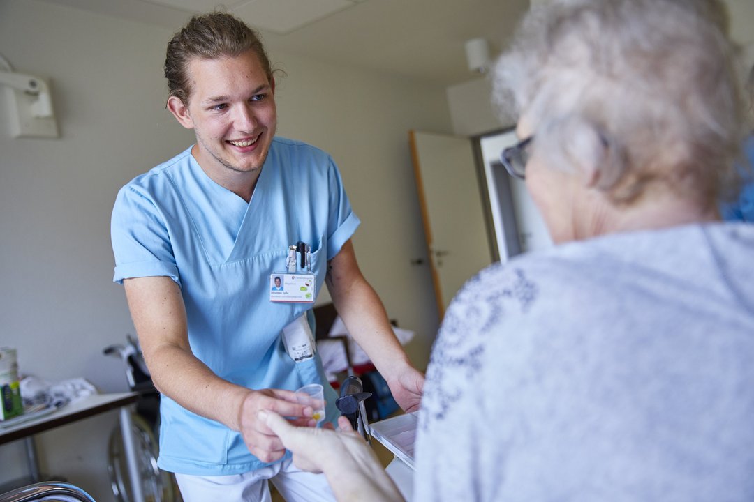 Ein Krankenpfleger bringt einer Patientin Medikamente
